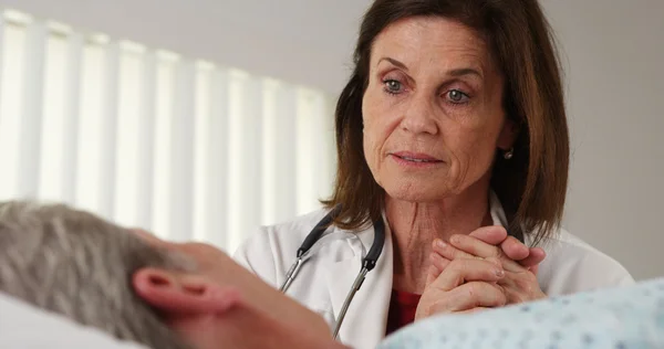 Senior doctor comforting elderly patient's hand — Stock Photo, Image