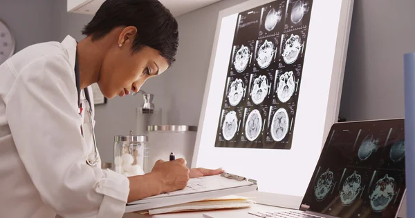 Afrikaanse medische vrouw leest x-ray resultaten van een brein — Stockfoto