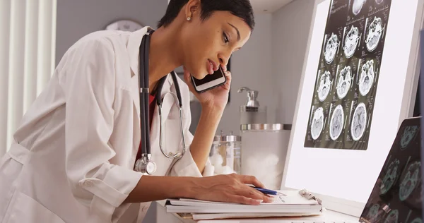 Siyah kadın doktor telefon ve x-ray taramaları okuma 