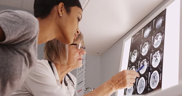 Intelligent mature female doctor viewing xrays with patient — Stock Photo, Image