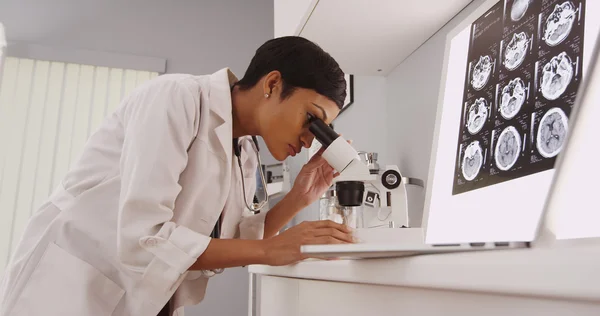 Jovem médica inteligente olhando em um microscópio — Fotografia de Stock