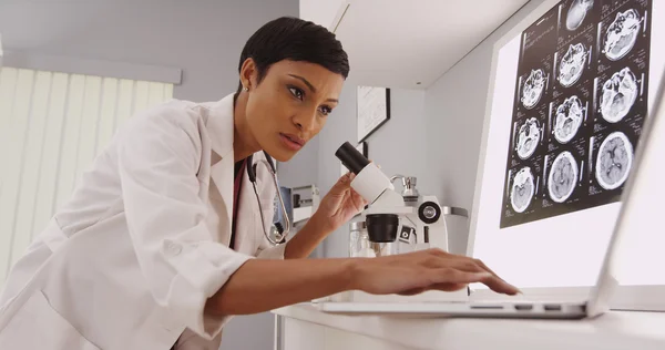 Young intelligent  female radiologist looking in a microscope — Stock Photo, Image