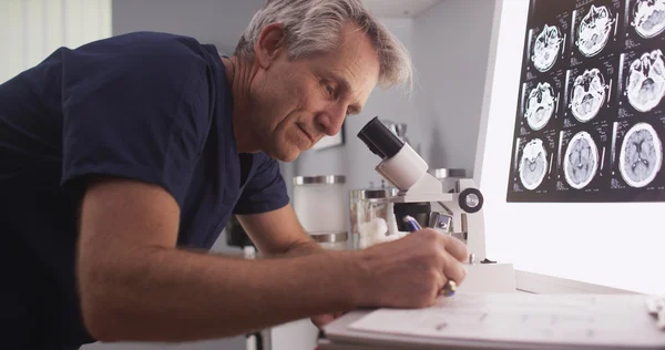 Radiólogo masculino de mediana edad mirando a través del microscopio — Foto de Stock