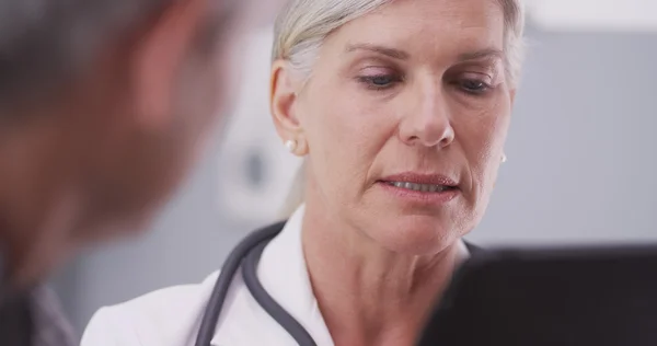 Średnim wieku kobieta lekarz patrząc na tabletki — Zdjęcie stockowe