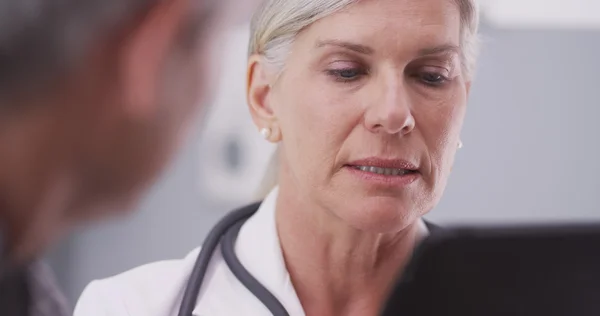 Médico femenino de mediana edad mirando una tableta —  Fotos de Stock