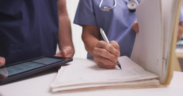 Close-up of mature female nurse writing in a patient's folder — Stock Photo, Image