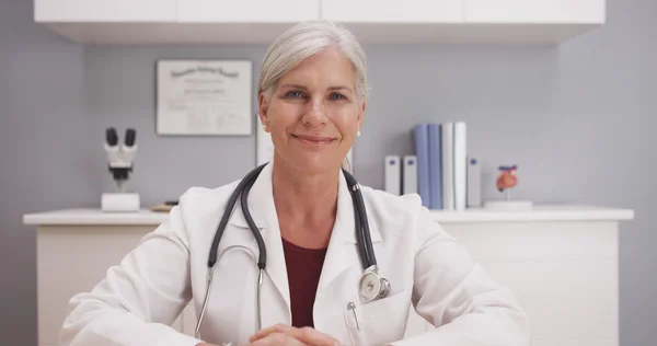 Smiling attractive mature female doctor talking to camera patient POV — Stock Photo, Image