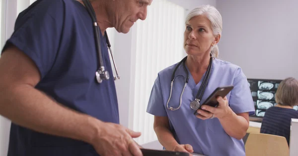 Dois médicos brancos maduros ou enfermeiros em dispositivos tecnológicos — Fotografia de Stock