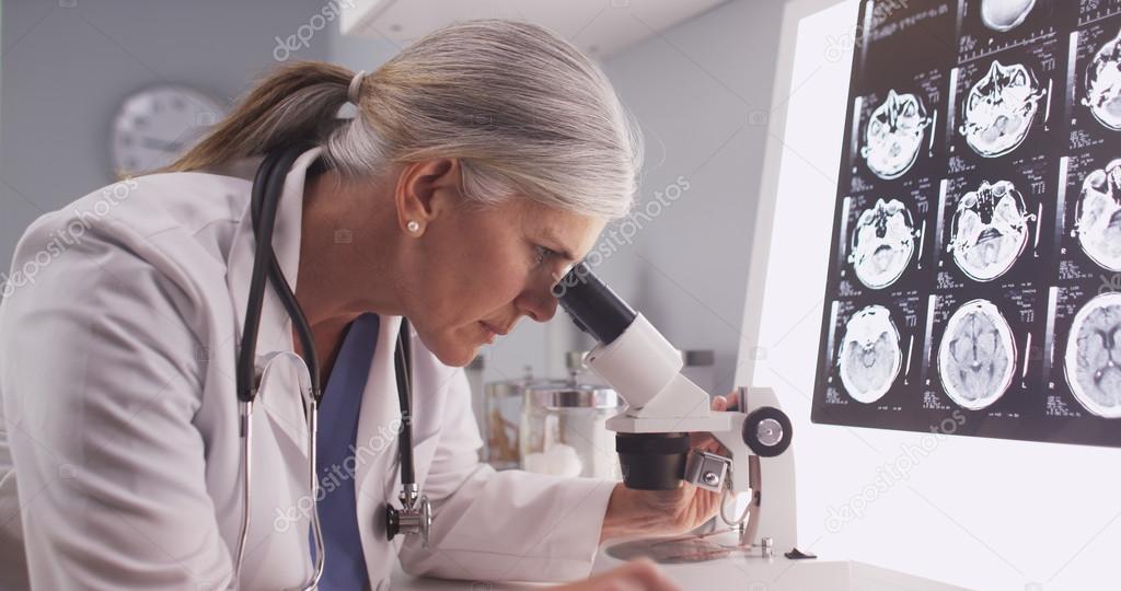 Mature white neurologist female looking at x-rays