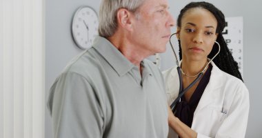 Afrikalı kadın doktor yaşlı hasta nefes alışını dinliyorum