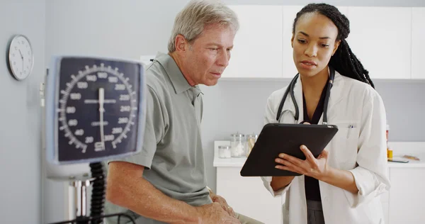 Black woman doctor talking with senior patient in the office