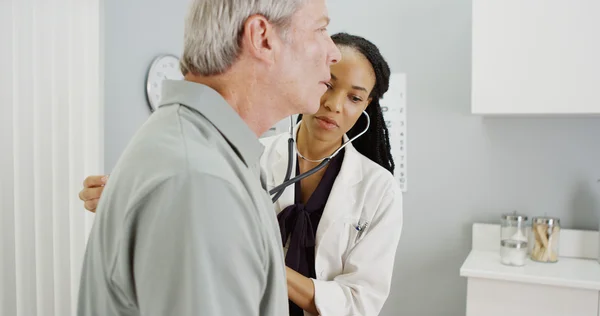 Mujer negra doctora escuchando respiración senior — Foto de Stock