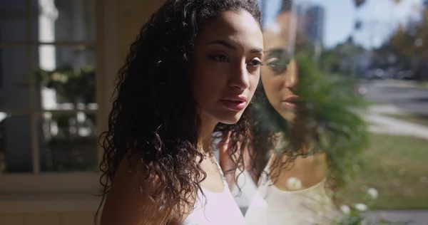 Charming young female hispanic looking through a window — Stock Photo, Image