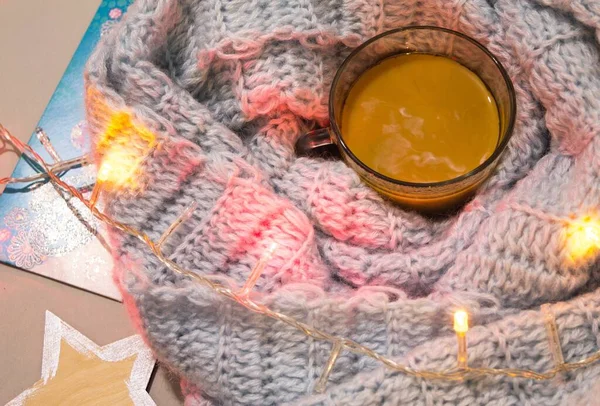 Mavi ekose ve çelenkli bir masanın üzerinde sütlü bir fincan kahve. Kış tatili atmosferi.