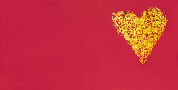 Kırmızı arka planda parıltılı altın bir kalp ve metin için yer var. Sevgililer Günü, Uluslararası Kadınlar Günü.