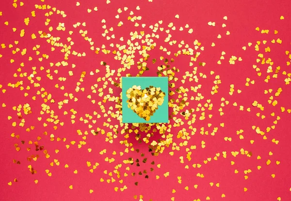 Kırmızı arka planda kalp şeklinde altın parıltılarla kaplı bir hediye kutusu ve metin için bir yer. Sevgililer günün kutlu olsun Flat Lay Sevgililer Günü, Uluslararası Kadınlar Günü. Tatil günü. Düz Yatay