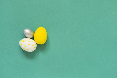 Yeşil arka planda üç renkli yumurta ve mesaj için boş bir yer. Mutlu Paskalyalar