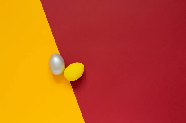 Renkli sarı ve kırmızı arkaplanlı paskalya kartında iki renkli yumurta ve mesaj için boş alan. Mutlu Paskalyalar