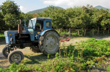 Eski Sovyet-Rus traktörü bir köyün ortasında duruyor.