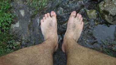 Genç adam, erkek nehir suyunda çıplak ayakla duruyor.