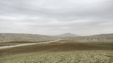 Ana yolun kenarındaki, sade sarı-gri manzaralı tarım arazisi. Tarla ekimi ekime hazır.