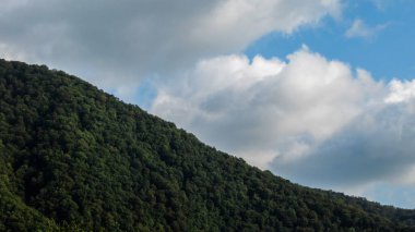 Kafkasya 'nın yeşil dağına yakın ve bulutlu mavi gökyüzüne
