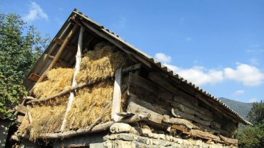 Köyde saman yığınları olan eski ahşap bir ahır.