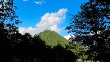 Büyük yeşil Kafkas dağ ormanlarının ve beyaz bulutlu mavi gökyüzünün güzel manzarası.