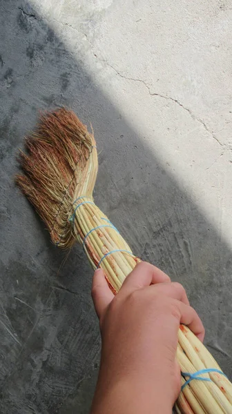 Male hand holding a sweep for cleaning his backyard