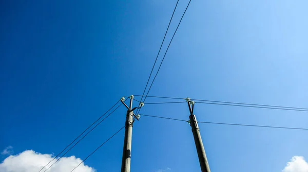 Power lines in front of a blue sky.