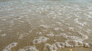 Deniz suyu kıyıya sakin bir dalgayla gelir.