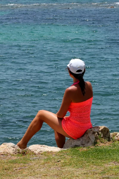 Hermosa chica sentada en una roca junto al mar —  Fotos de Stock