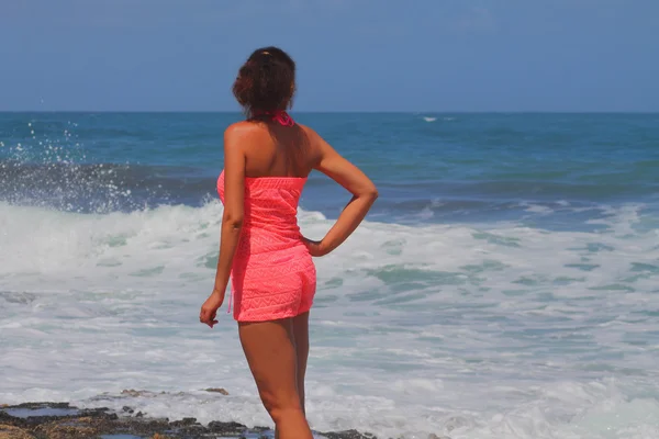 Красивая девушка в красном смотрит на море — стоковое фото