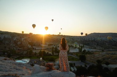 Genç bir bayan sıcak hava balonunu izliyor.