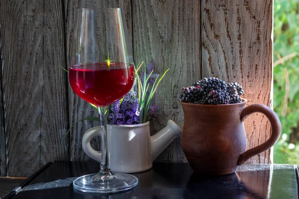 Glass of red wine with blackberries as snack. Simple ceramic dishes, rustic style. Topic - background for menu, for congratulations, on topic. On topic of winemaking .
