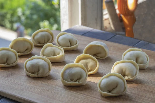 Dumplings with minced meat raw on cutting board. Freshly made dumplings. Dumplings with meat - one of best dishes of Russian cuisine, light and at same time satisfying food .