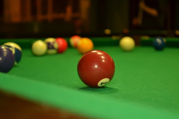 Billiard ball number seven is on green table aside other balls — Stock Photo, Image