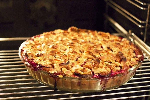 Freshly baked plum pie with almonds and crumble on top in the ov — Stock Photo, Image