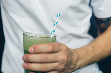 Bir bardak yeşil smoothie tutan adam