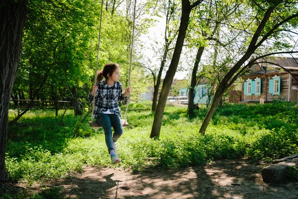 Дівчина їде на гойдалці в селі — стокове фото