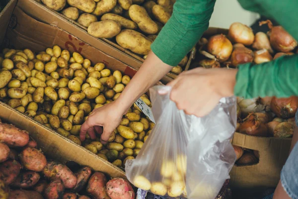 kadın bir paket yeni patates piyasada koyar.