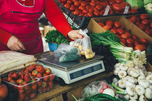 the seller is weighing vegetables on scales