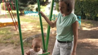 Kızı salıncak üzerinde sallanan kadın