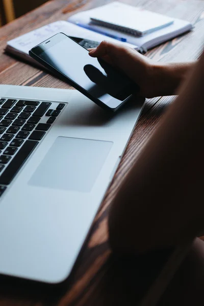 Mujer trabajando en la computadora y mirando el teléfono — Foto de Stock