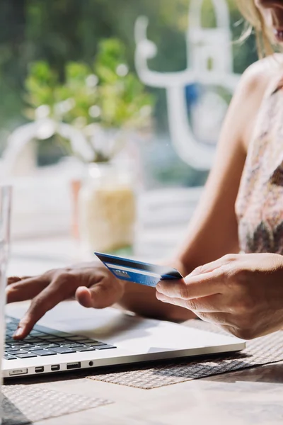 Mujer usando el ordenador portátil con tarjeta de crédito en la mano — Foto de Stock