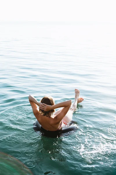 Rahatlatıcı kadının şişme halkada yüzen arkadan görünüm — Stok fotoğraf