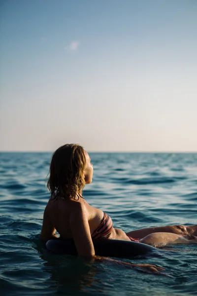 Rückansicht einer entspannten Frau, die auf einem aufblasbaren Ring schwimmt — Stockfoto