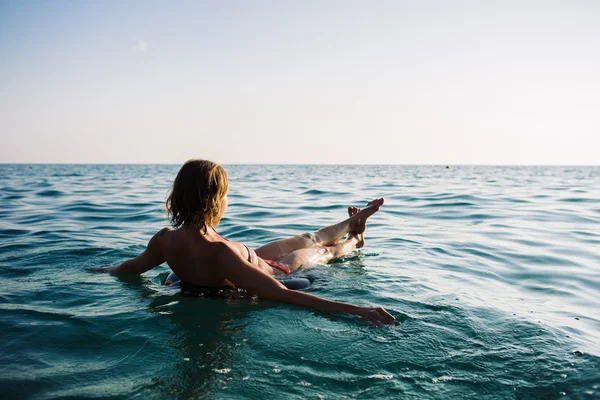 Вид ззаду розслабляюча жінка, що плаває на надувному кільці — стокове фото
