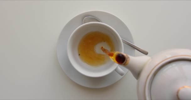 El té de la tetera se vierte lentamente en la taza de porcelana — Vídeo de stock