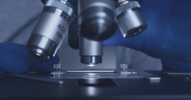 Образец слайда и микроскопа с металлическим объективом в лаборатории. — стоковое видео
